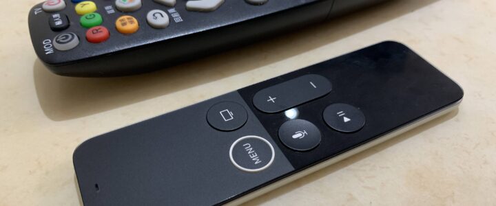 照片中有兩個遙控器，上面的電視遙控器有很多實體按鍵，下面的Apple TV遙控器上面只有六個實體按鍵，操作時要搭配電視螢幕中出現的虛擬按鍵