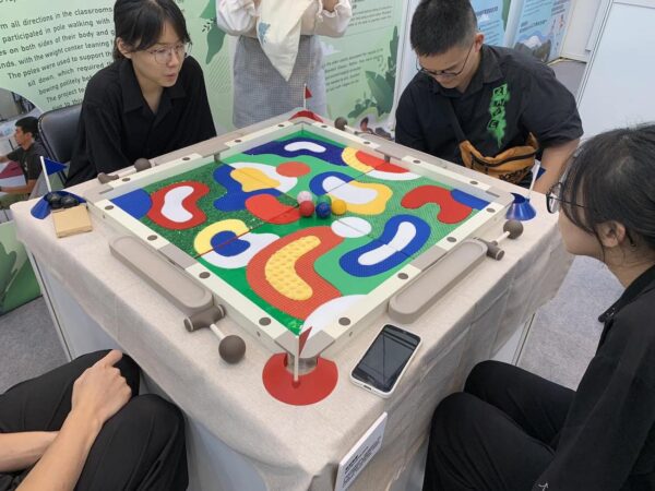 四人正在玩桌遊。此桌遊是採用了紅藍黃綠白等多種顏色，搭配細毛、顆粒、凹洞等不同紋理與材質，讓視力不好的人也能一起玩。